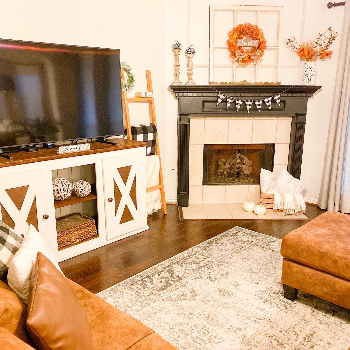 Cozy fall living room with a fireplace, autumn wreath, plaid accents, and warm-toned decor creating a welcoming seasonal ambiance