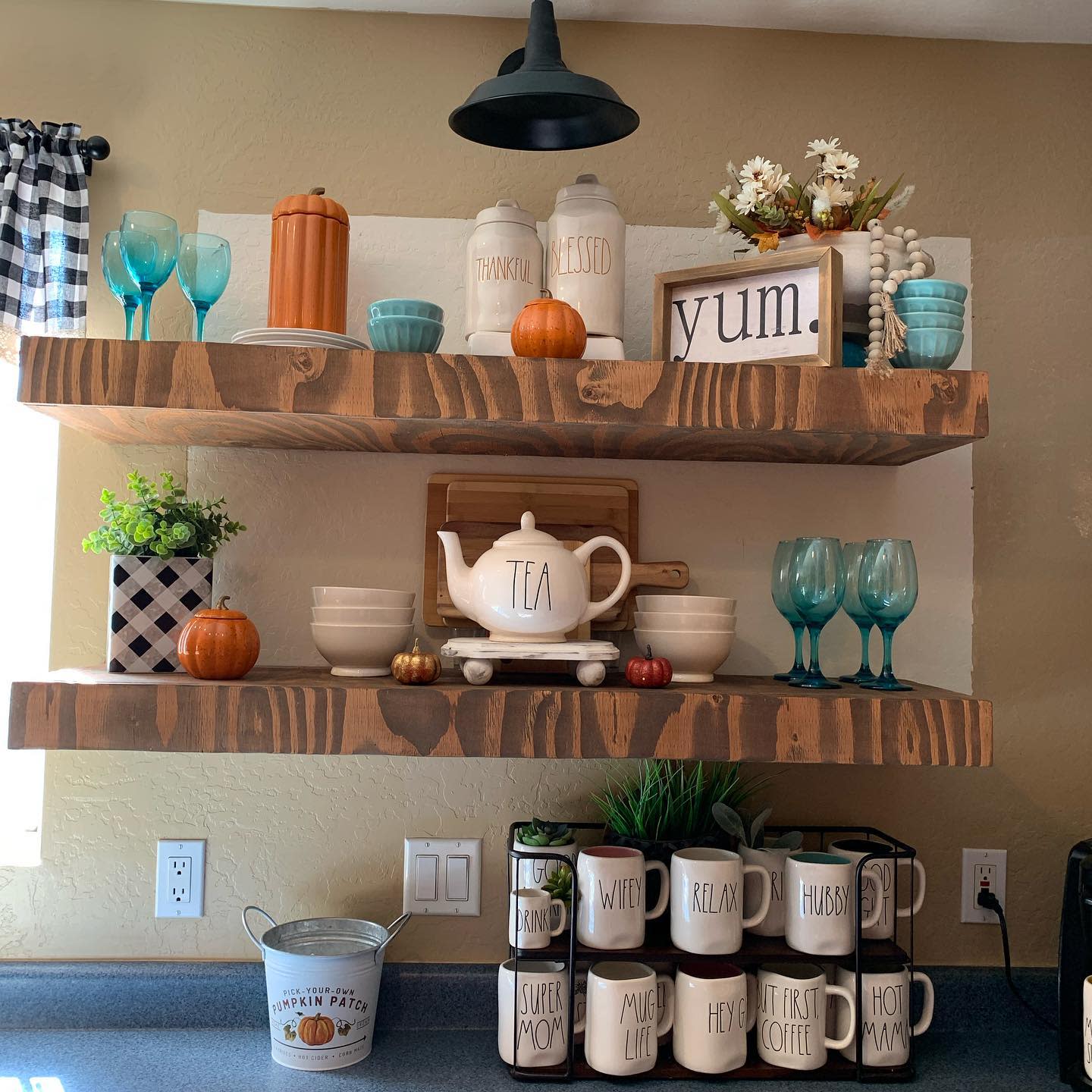 Rustic open kitchen shelves decorated with fall accents, Rae Dunn mugs, pumpkins, and a cozy mix of blue and neutral tones