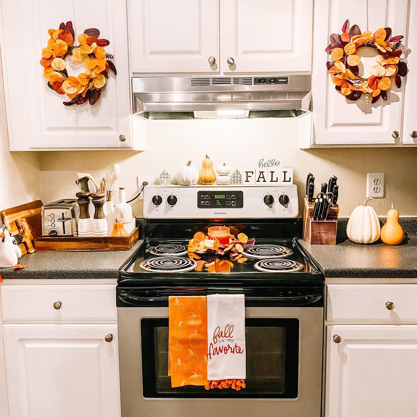 Fall-themed kitchen with autumn wreaths, pumpkins, seasonal towels, and warm decor accents creating a cozy seasonal look