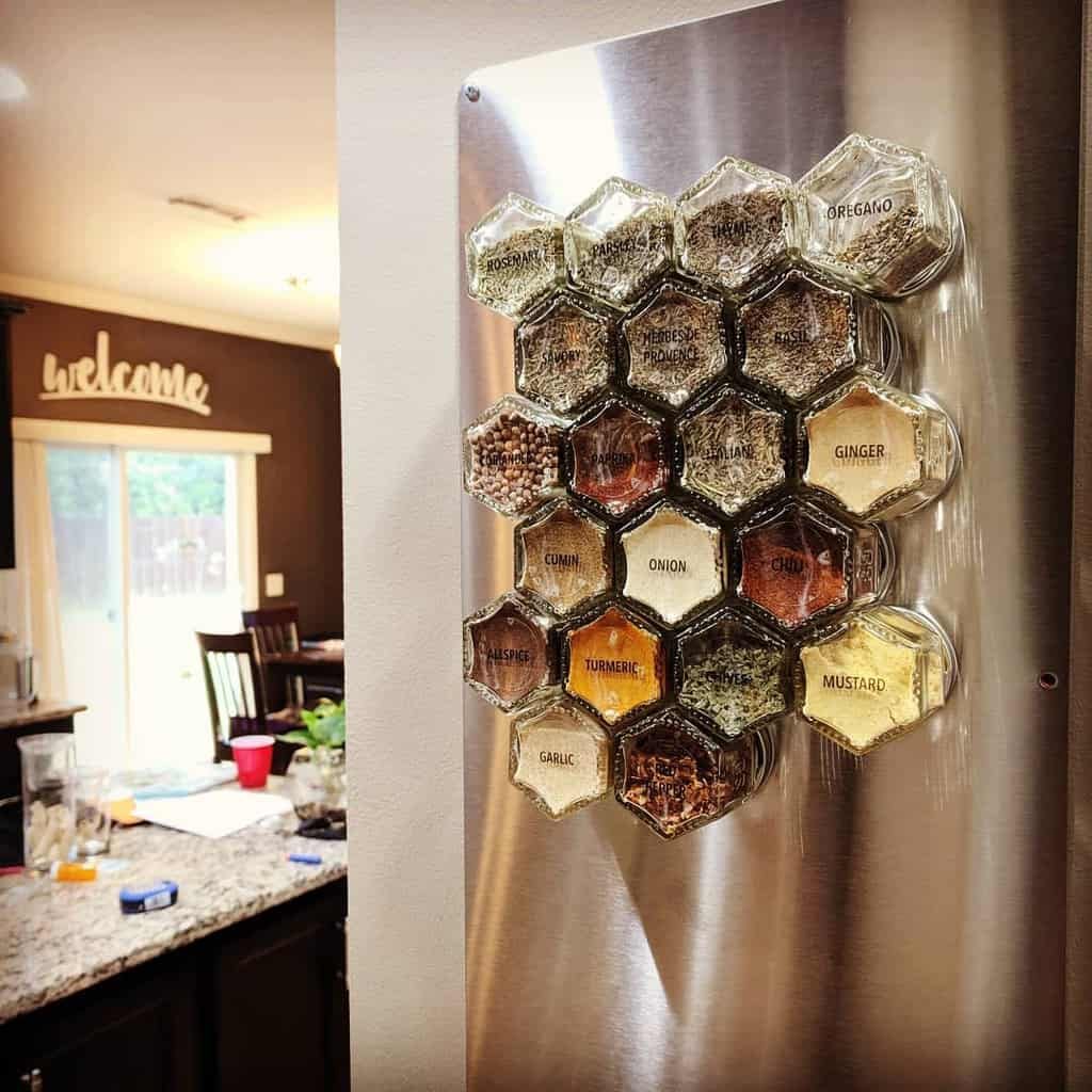 Hexagonal magnetic spice jars arranged on a stainless steel panel, creating a stylish and space-saving kitchen storage solution