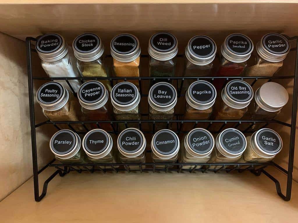 Spice rack filled with labeled jars including baking powder, dill weed, and chili powder, organized neatly on two shelves