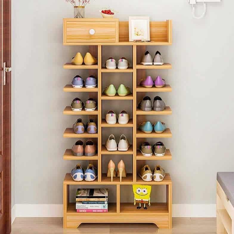 Wooden shoe rack with multiple pairs of shoes, a drawer, a photo frame on top, and a plush toy at the bottom