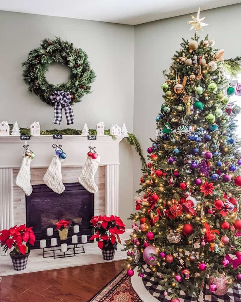 Festive Christmas room with decorated tree, wreath on wall, stockings over fireplace, and poinsettias on floor