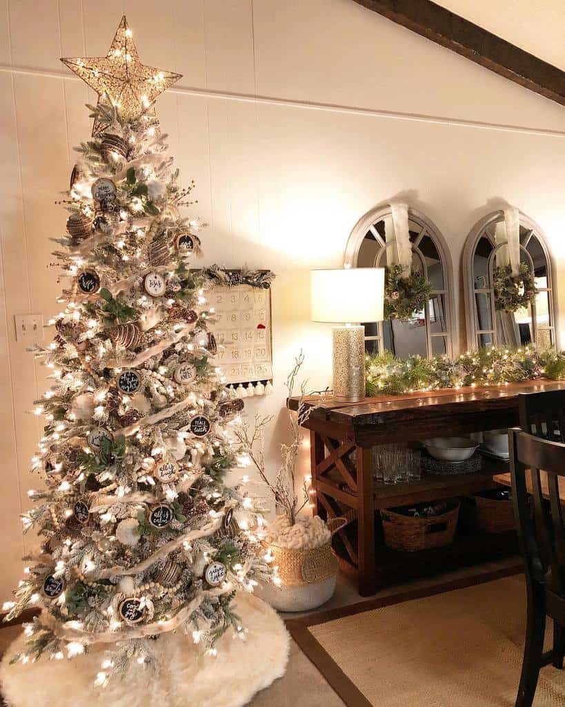 A decorated Christmas tree with a star topper and ornaments stands in a cozy room, nearby a table with a lamp and festive garland