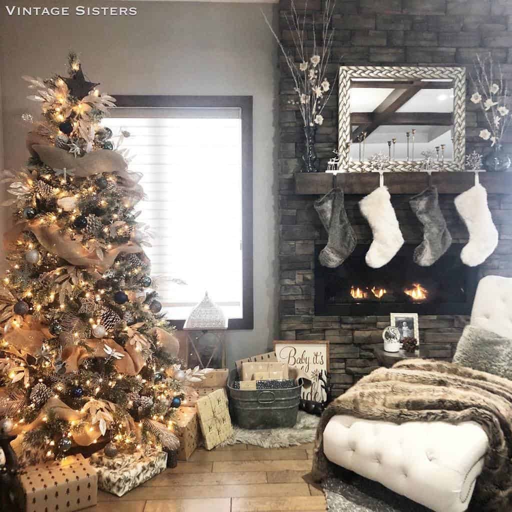 Cozy living room with a decorated Christmas tree, fireplace with stockings, and gifts; earth-toned decor and a plush chair