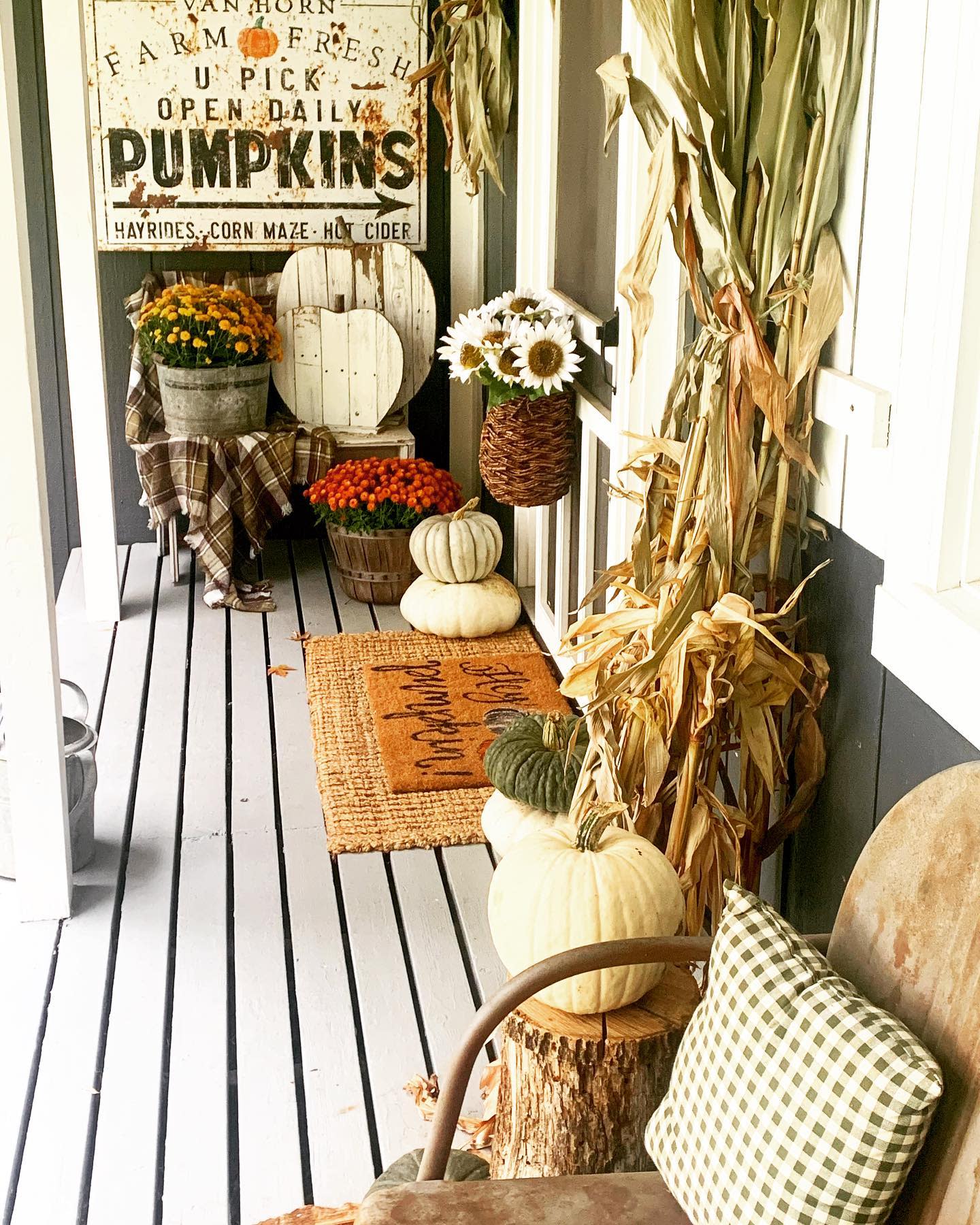 Cozy porch with pumpkins, mums, cornstalks, a vintage pumpkin sign, and a "Welcome" mat