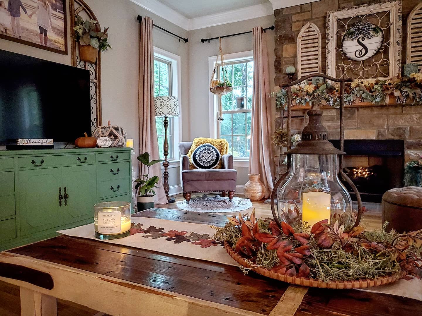 Cozy living room with an armchair, green cabinet, and a decorated fireplace; rustic lantern centerpiece on a wooden table