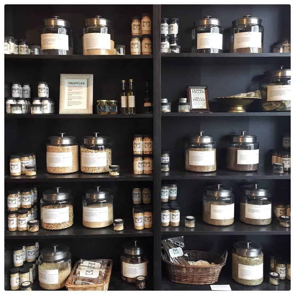 Shelves stocked with various jars and baskets containing spices and seasonings, labeled and organized for display