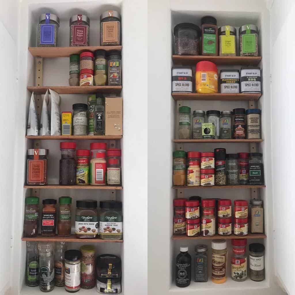 Neatly organized spice racks filled with various jars and bottles of spices on wooden shelves