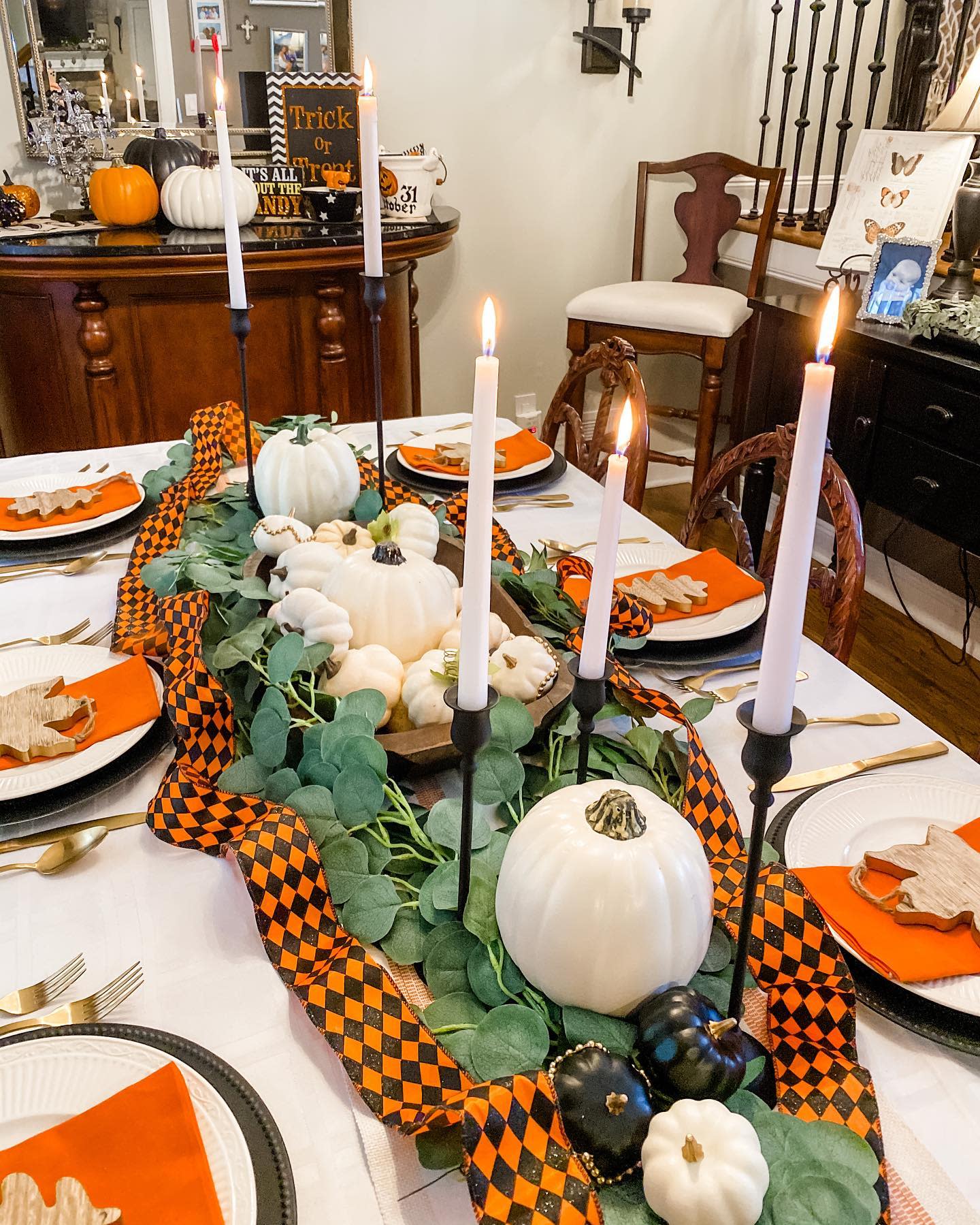 A Halloween-themed dinner table with pumpkins, candles, and black-orange decorations