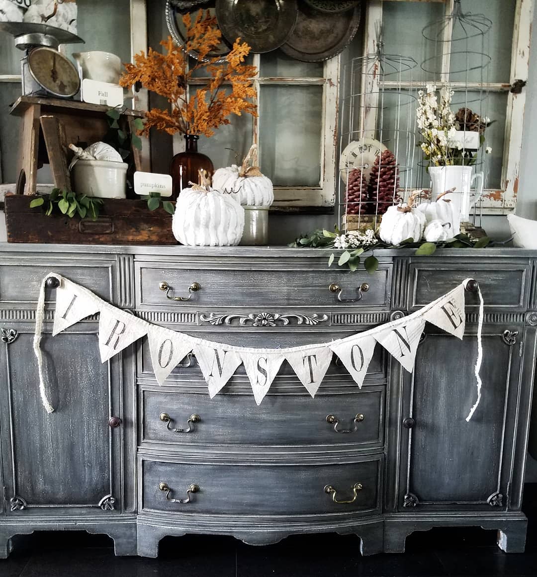 Vintage sideboard with fall decor: white pumpkins, pinecones, and autumn leaves featuring an "Ironstone" banner draped across the front