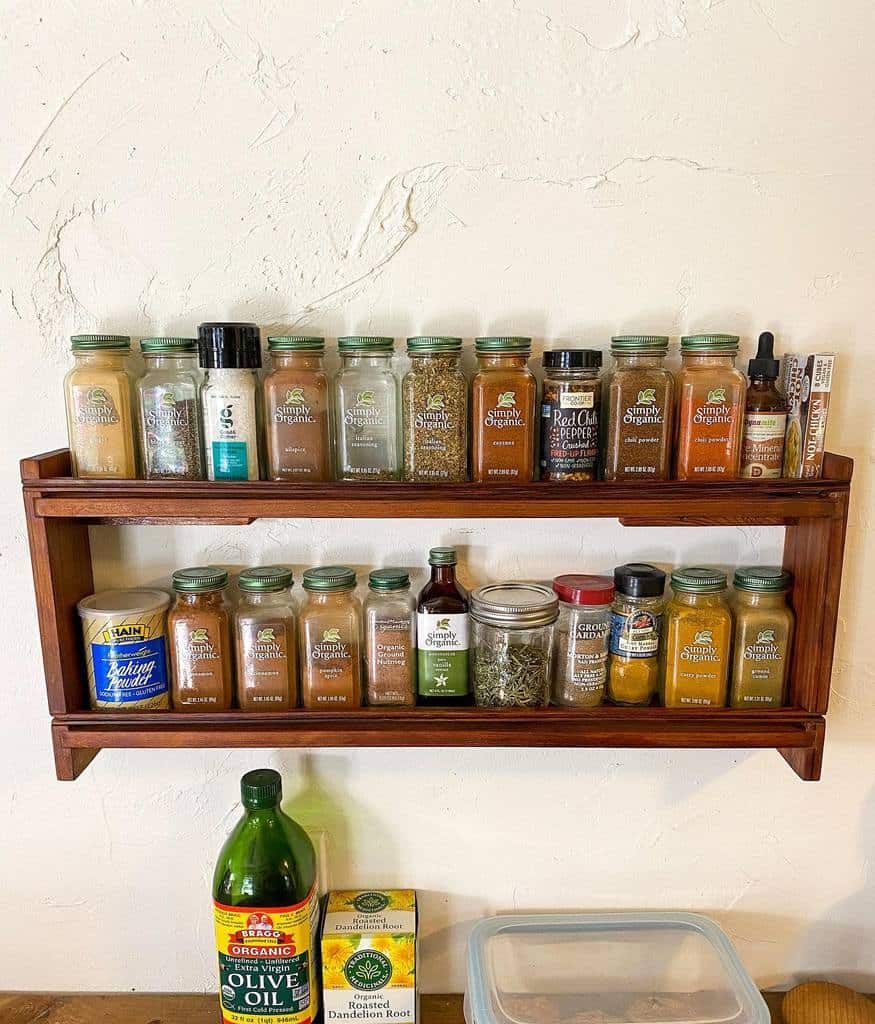 Rustic wooden wall spice rack with neatly arranged organic spice jars, adding charm and functionality to a cozy kitchen space