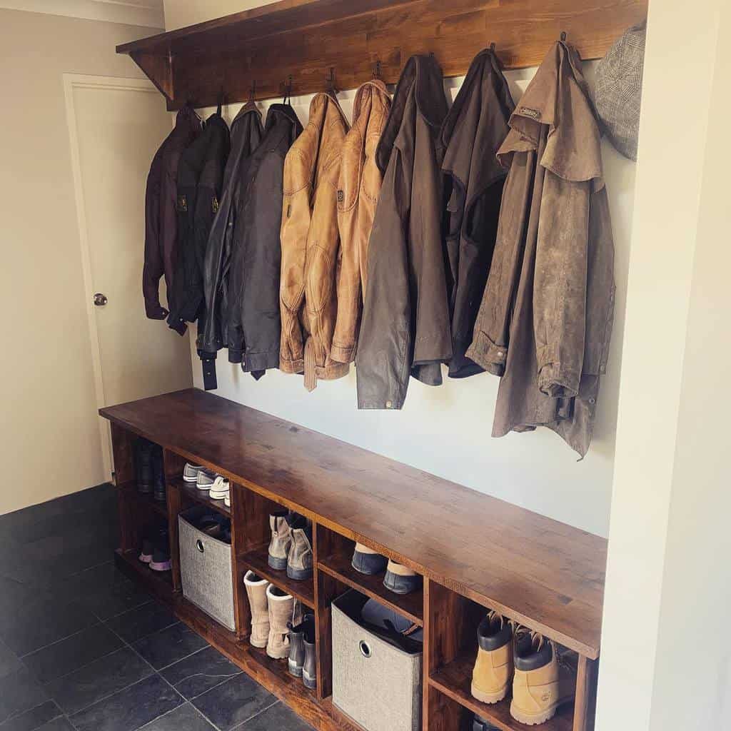 Wooden mudroom bench with hooks holding jackets, and cubbies storing shoes and baskets underneath