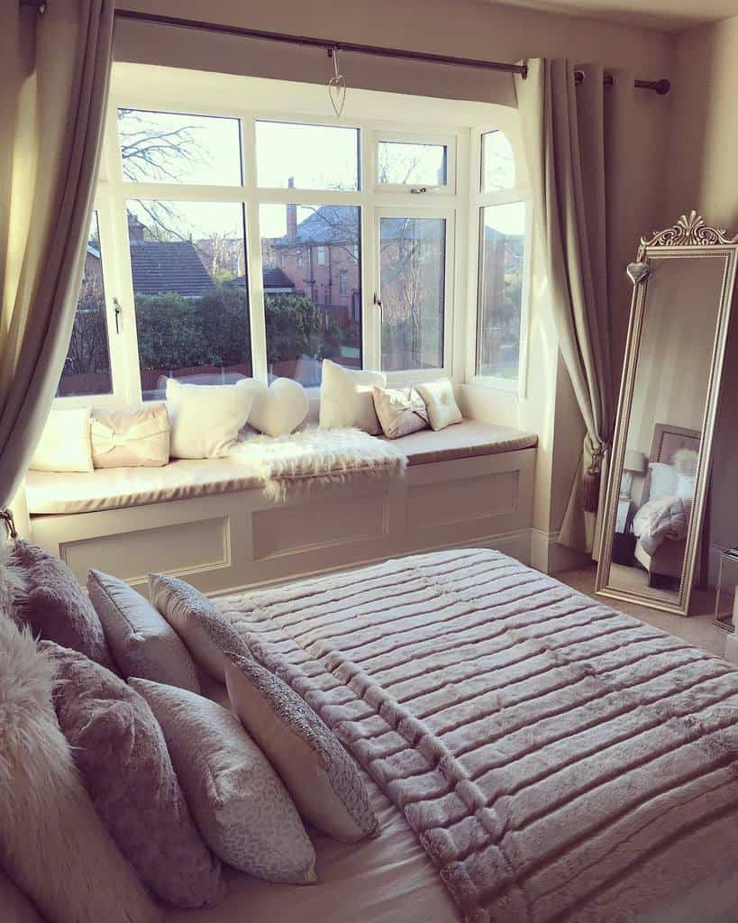 Cozy bedroom bay window with a built-in bench, plush cushions, and soft throws, creating a serene nook for relaxation.