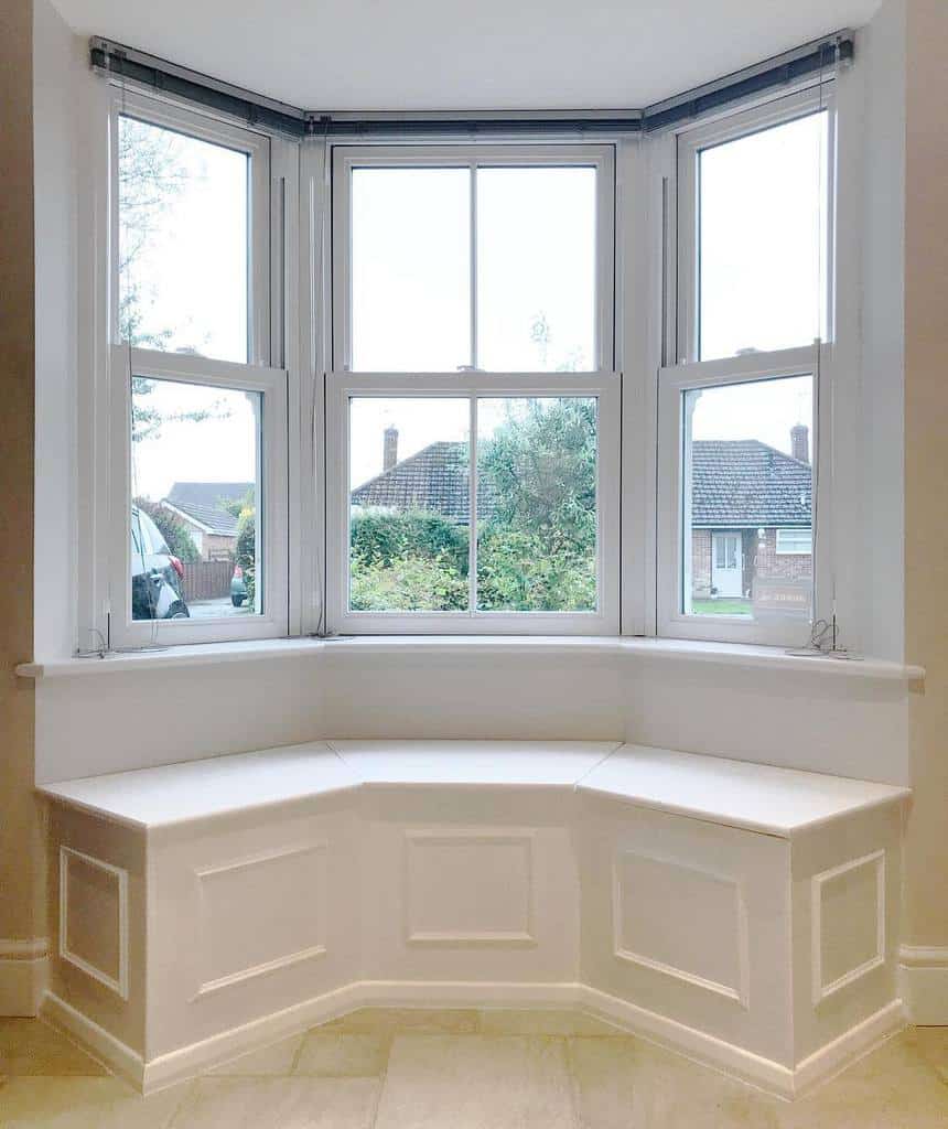 Minimalist bay window with a built-in white bench, offering a bright and airy space perfect for a cozy seating or storage solution.