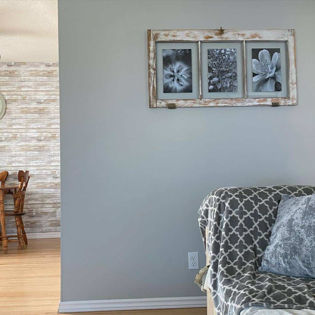 Rustic old window frame repurposed as a wall art piece, featuring three black and white floral prints, hanging in a cozy living space.