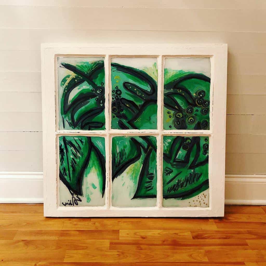 Repurposed old window frame with abstract green and black hand-painted artwork, creating a unique decorative statement piece.