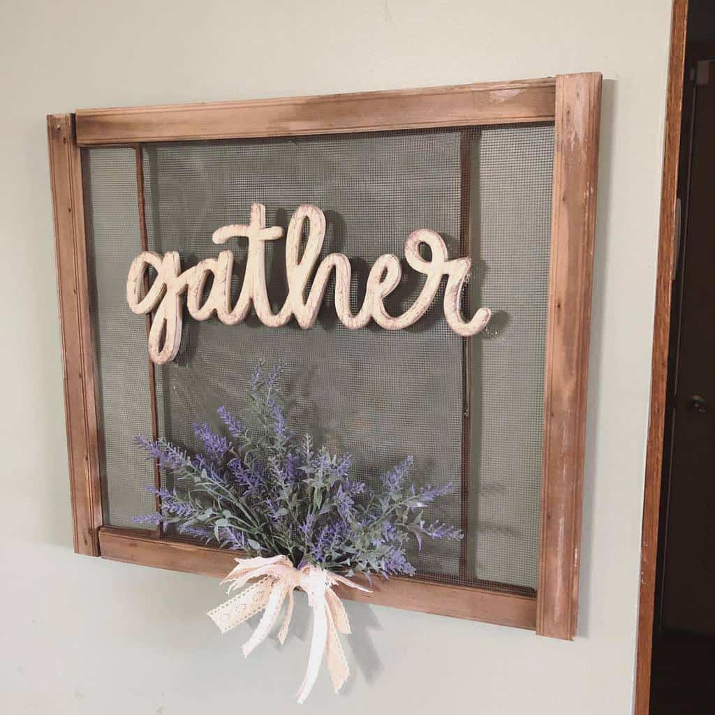 Repurposed old window screen turned into farmhouse wall decor, featuring a 'gather' sign and a lavender bouquet tied with a lace ribbon.