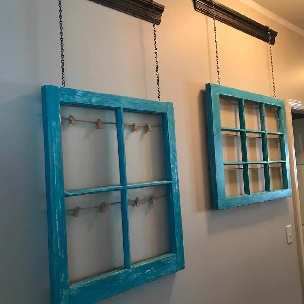 Repurposed old window frames painted distressed turquoise, hanging from chains as shabby chic wall decor, one with mini clothespins for display.