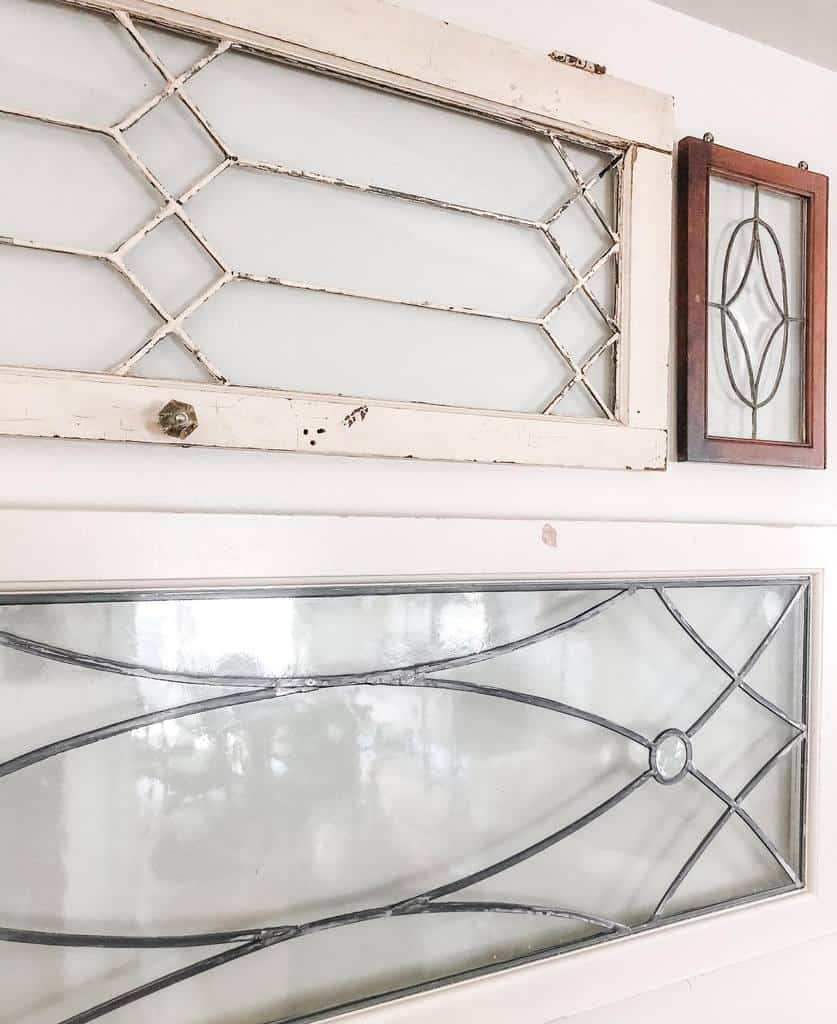 Collection of vintage leaded glass windows in various sizes and finishes, repurposed as elegant wall decor for a shabby chic look.