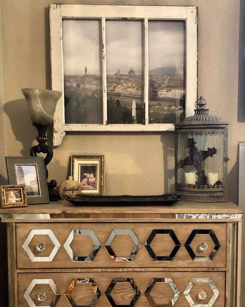 Repurposed old window frame turned into wall art, featuring a cityscape print behind glass, styled with vintage decor on a mirrored dresser.