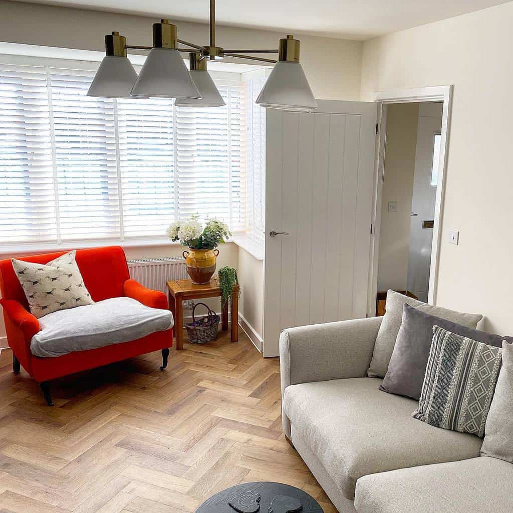 Modern living space with a square bay window, white blinds, a bold red accent chair, and neutral decor, creating a stylish and cozy ambiance.