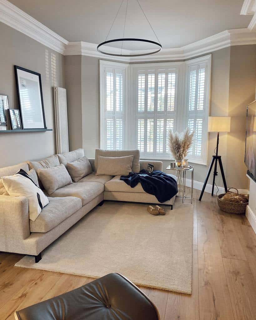 Elegant Victorian bay window living room with white plantation shutters, a cozy neutral-toned sectional, and modern decor for a timeless look