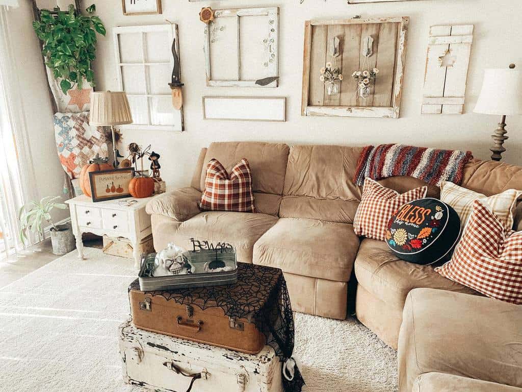 Cozy farmhouse living room with repurposed old window frames as wall decor, fall-themed accents, plaid pillows, and vintage-style furnishings.