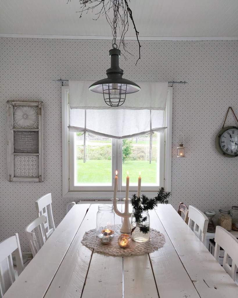 Bright farmhouse dining room with a white wooden table, vintage decor, a rustic pendant light, and a repurposed old window frame on the wall.