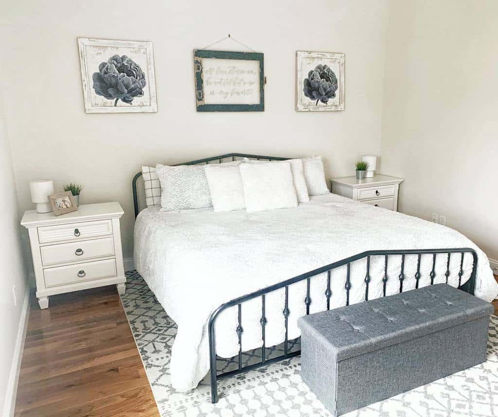 Bright bedroom designed for small spaces, featuring a metal bed, fluffy white bedding, two nightstands, wall art, and a gray bench at the foot.