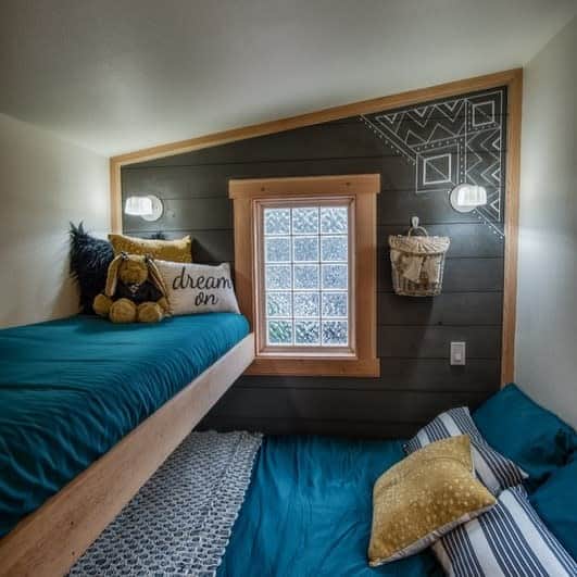 Cozy loft that showcases small spaces design ideas with the top bunk featuring teal bedding and a stuffed animal, and the bottom bunk adorned with gold pillows.