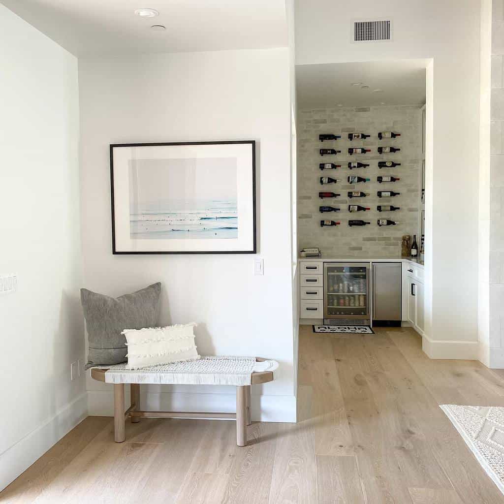 Minimalist entryway with a wooden bench, textured pillows, and coastal artwork, creating a serene and inviting space