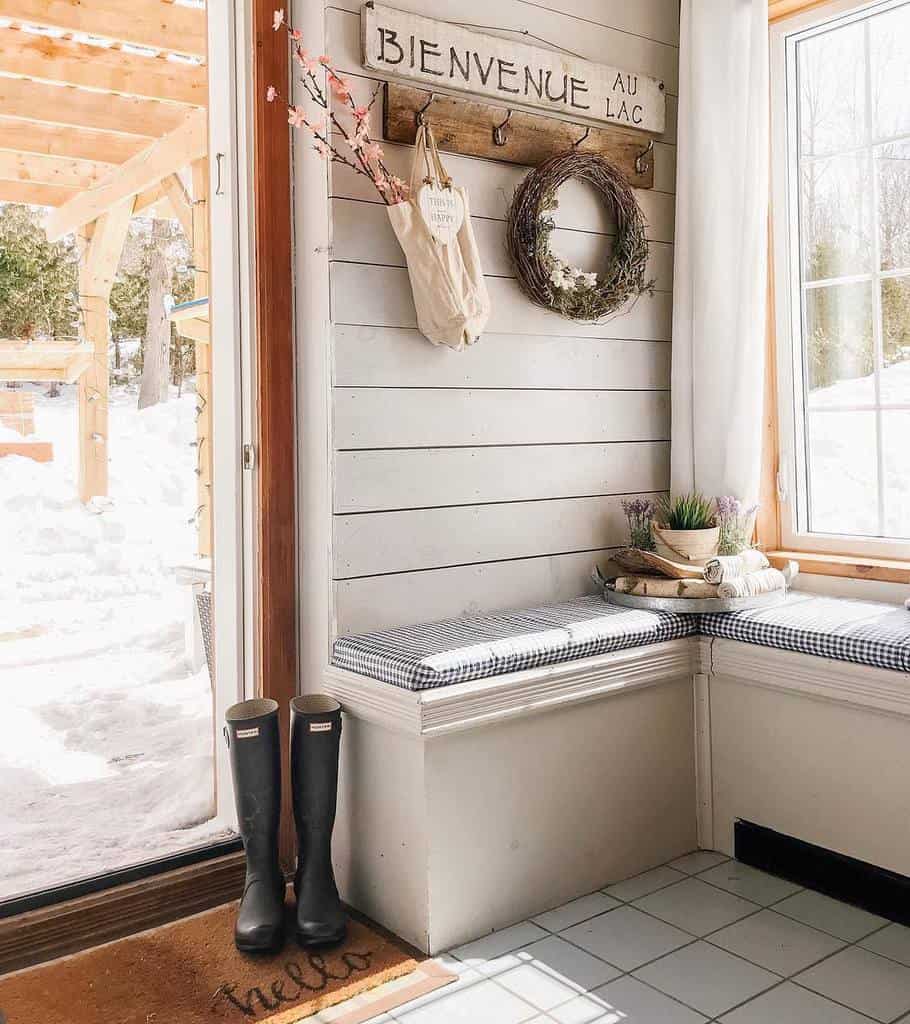 Cozy lake house entryway with built-in bench seating, shiplap walls, rustic decor, and a welcoming sign for a warm cottage feel