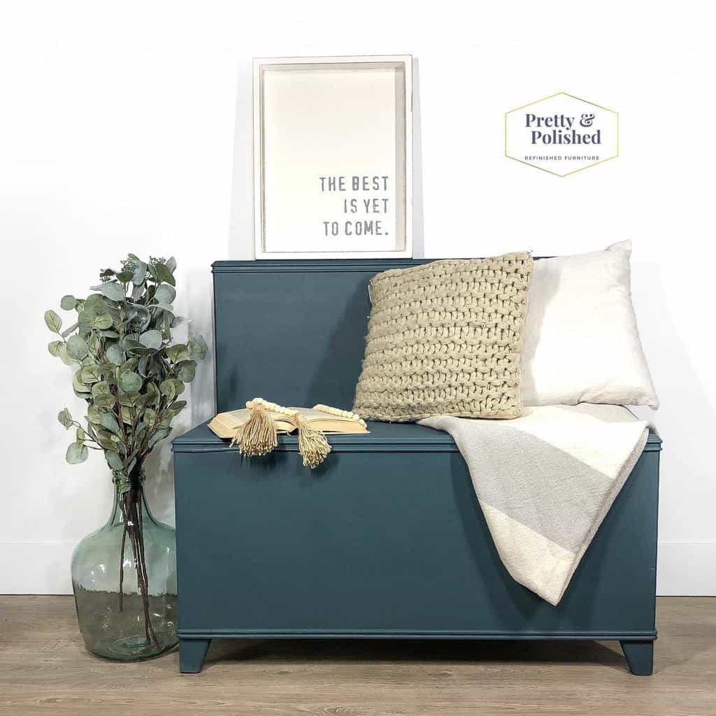 Stylish entryway with a deep blue storage bench, cozy pillows, a woven throw, and decorative greenery for a warm, inviting feel