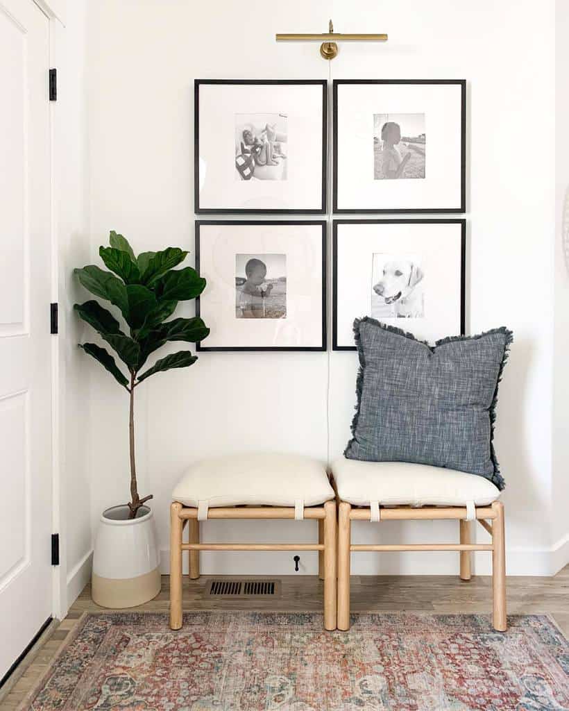 Modern entryway with two wooden stools, a cozy pillow, a fiddle leaf fig, a vintage rug, and a gallery wall with black-and-white photos