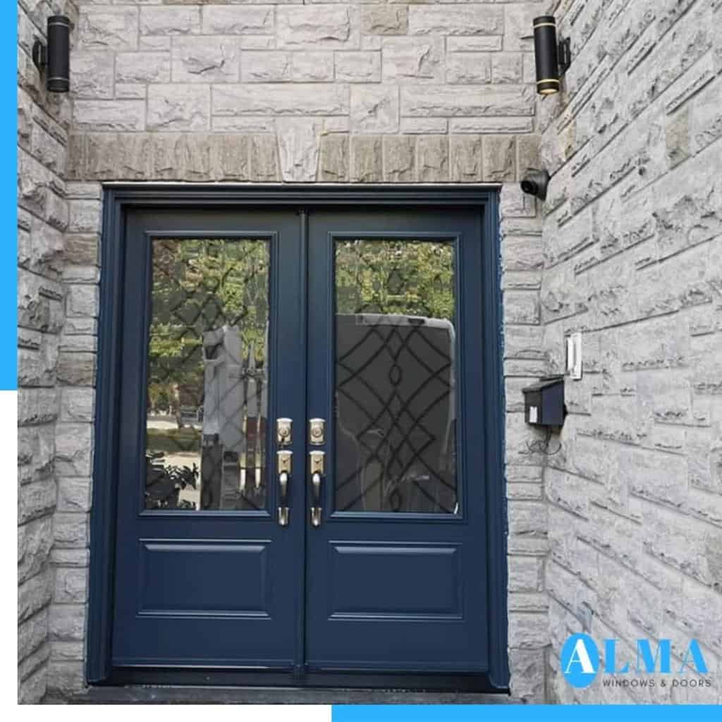 Blue double doors with glass panels set in a stone wall, flanked by black lanterns and a mailbox fixed to the right