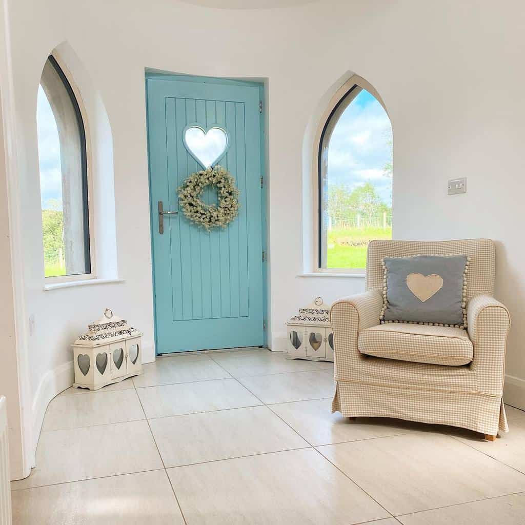 Cozy foyer with a blue door featuring a heart-shaped decoration, flanked by two arched windows