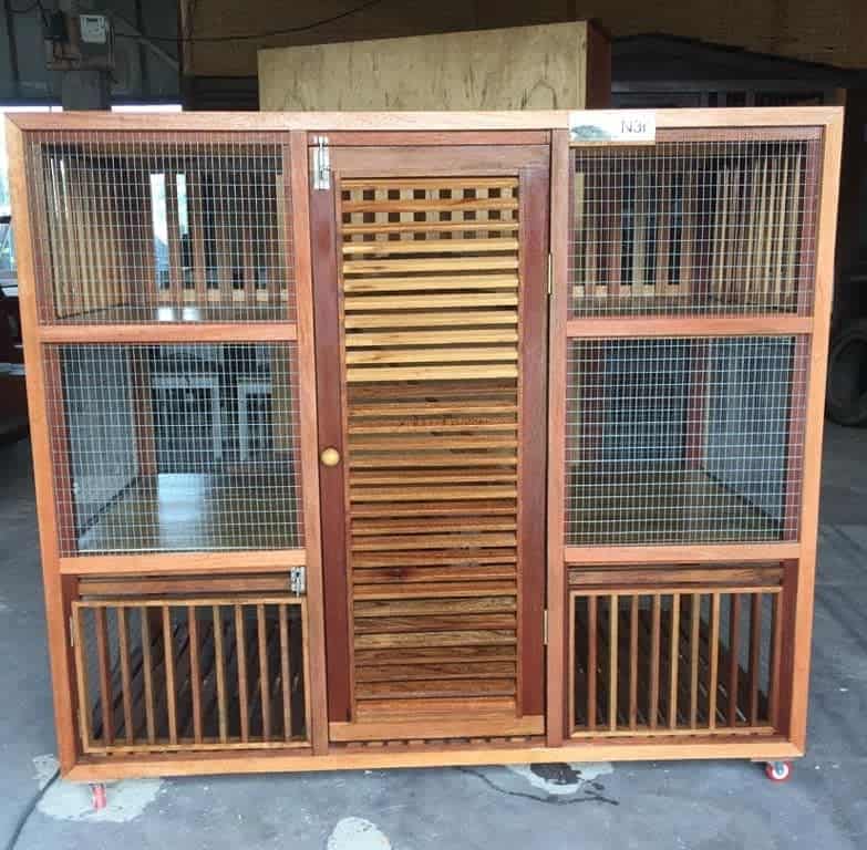 Wooden catio with mesh panels, a slatted door, multiple levels, and rolling wheels for mobility, offering a secure outdoor space for cats