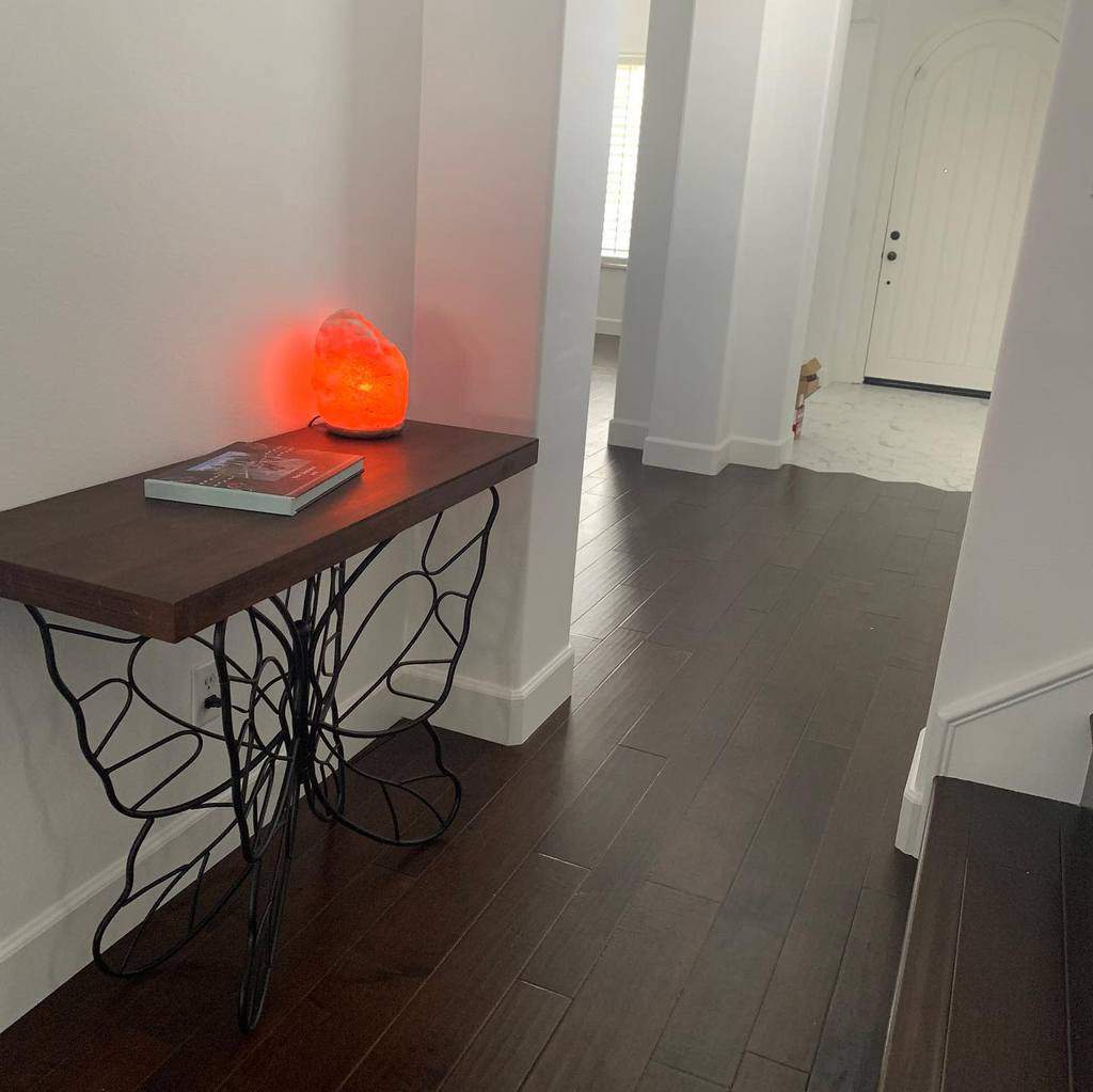 Stylish entryway with a unique butterfly-inspired console table, a glowing Himalayan salt lamp, and dark hardwood floors