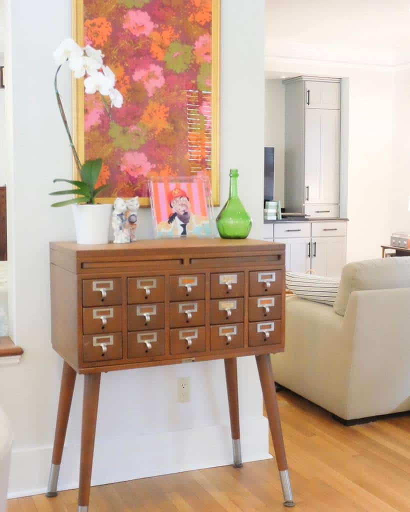 Eclectic entryway with a vintage card catalog cabinet, bold floral artwork, an orchid plant, and colorful decor accents for a retro charm