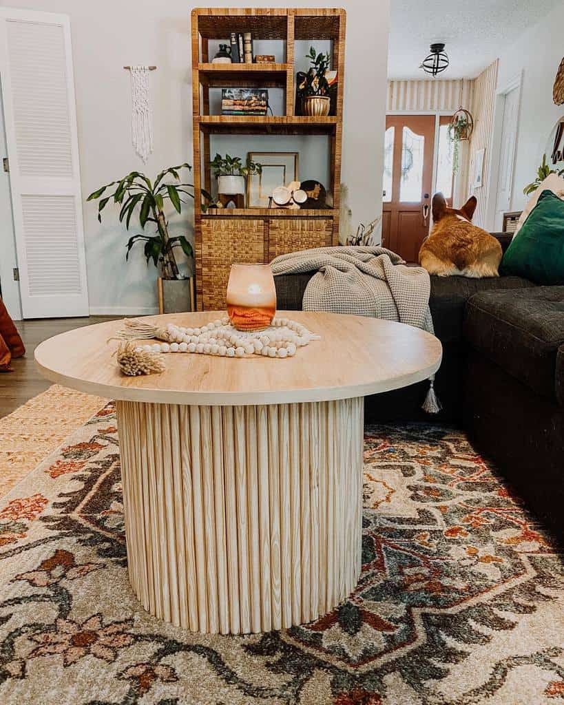 Round wooden coffee table with a fluted base, styled with beads and a candle, set in a cozy boho living room with warm earthy tones