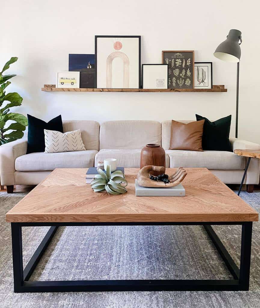 Modern rustic coffee table with a herringbone wood top and black metal frame, styled with books, decor, and a vase in a cozy living room