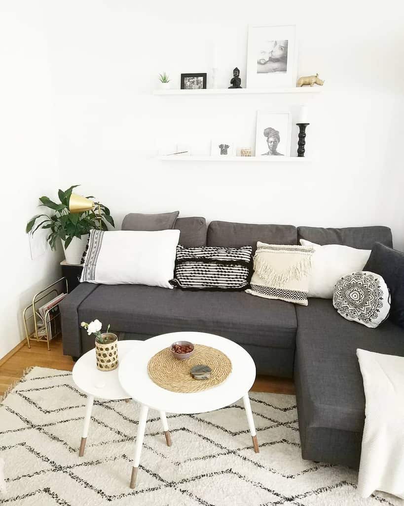 Minimalist set of white nesting coffee tables with wooden legs, styled with a woven placemat, vase, and decor, set in a cozy monochrome living room