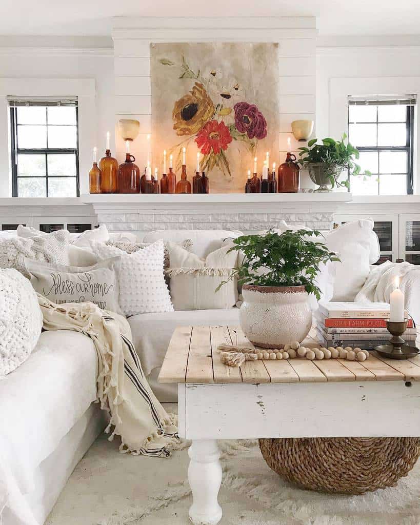 Rustic farmhouse coffee table with a wooden top and white legs, styled with a potted plant, books, beads, and a candle in a cozy living room