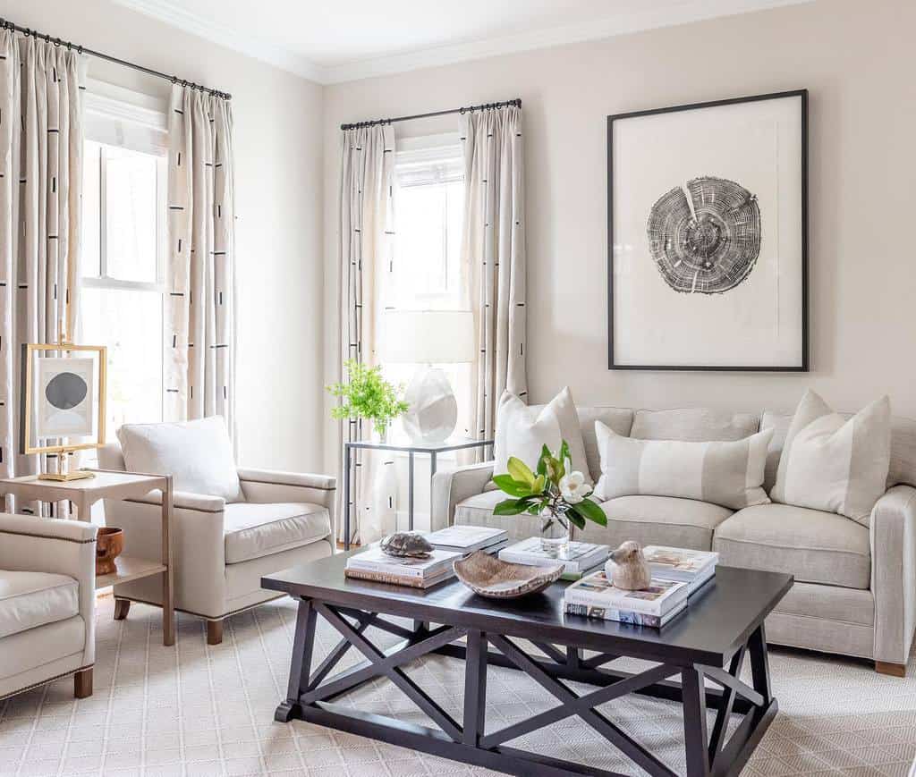 Black wooden coffee table with a geometric base, styled with books, a vase, and decorative pieces, set in a neutral-toned elegant living room