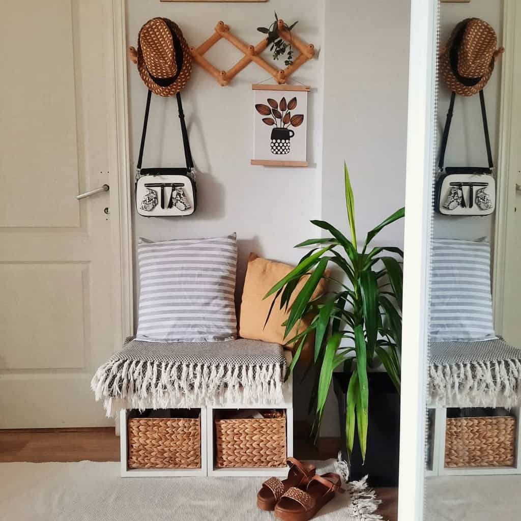 Cozy boho entryway with a small bench, woven storage baskets, soft cushions, wall-mounted hooks, and greenery for a warm, inviting feel