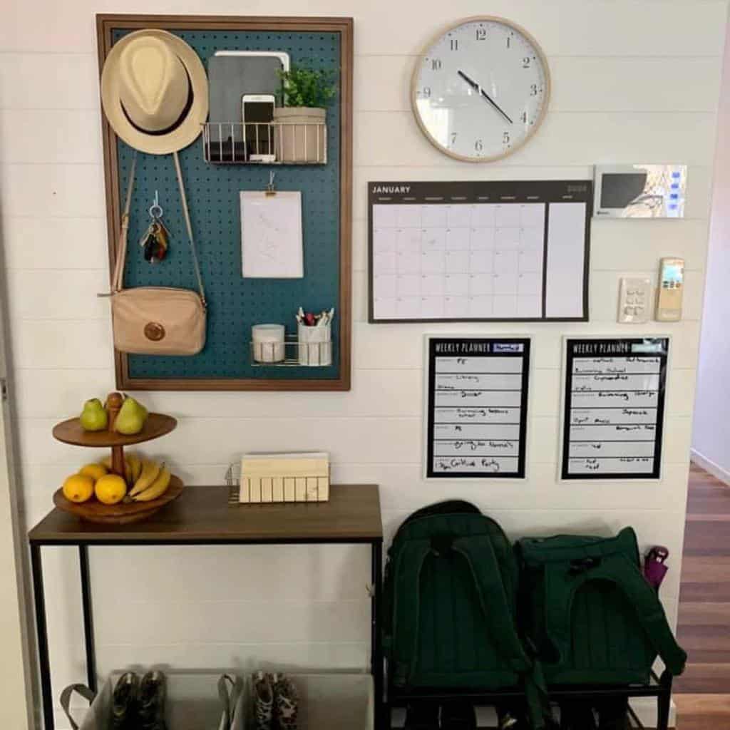 Functional entryway with a pegboard organizer, calendar planners, a sleek console table, and storage for shoes and backpacks