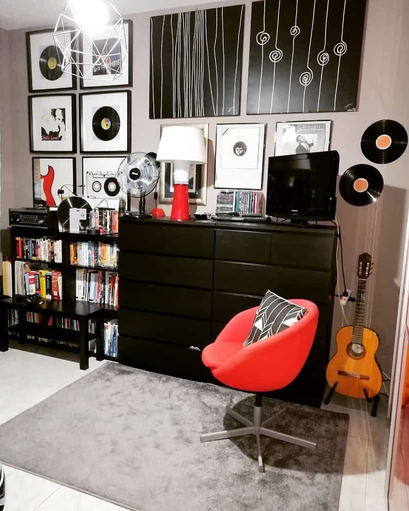 Stylish music-themed room with vinyl records, framed artwork, a black dresser, a red swivel chair, a guitar, and a modern bookshelf