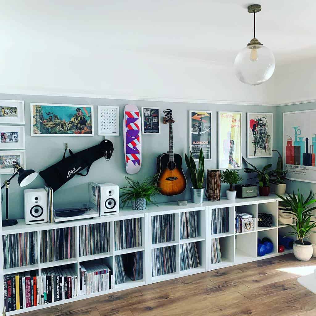 Modern music room with vinyl records, framed artwork, an acoustic guitar, plants, white storage shelves, and a sleek minimalist aesthetic