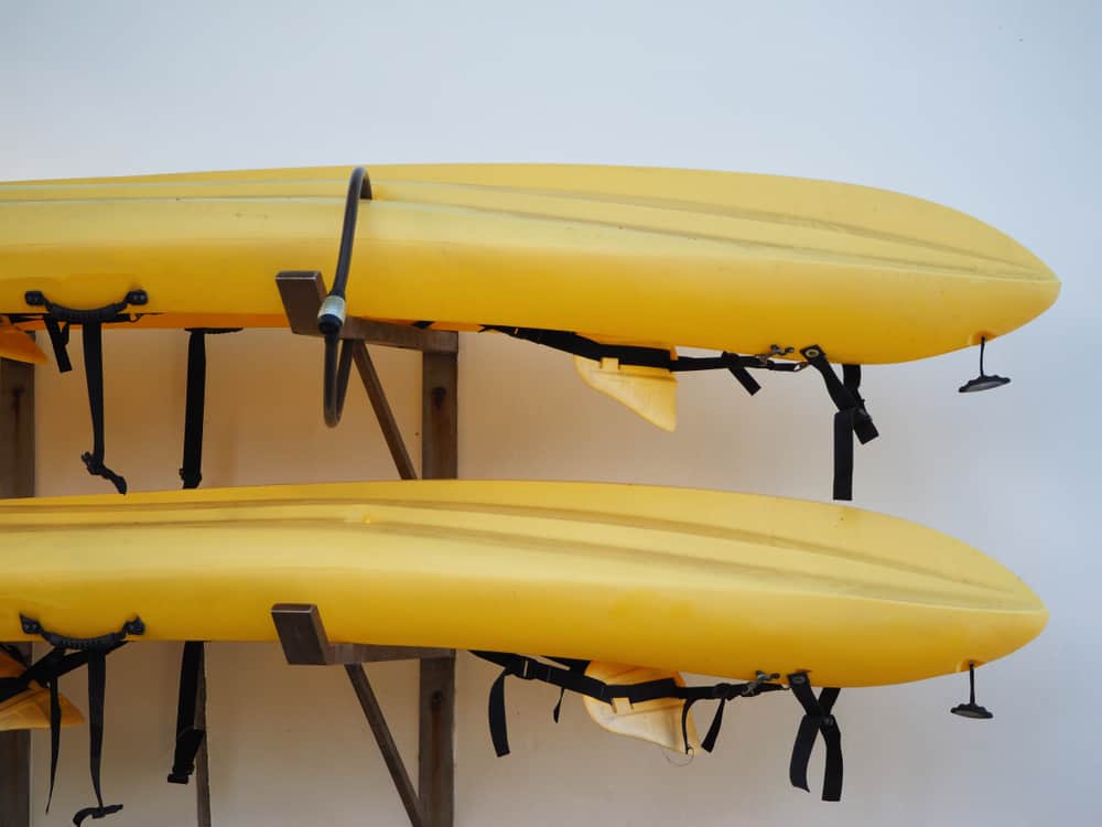 Two,Yellow,Kayaks,Are,Stored,Outside.